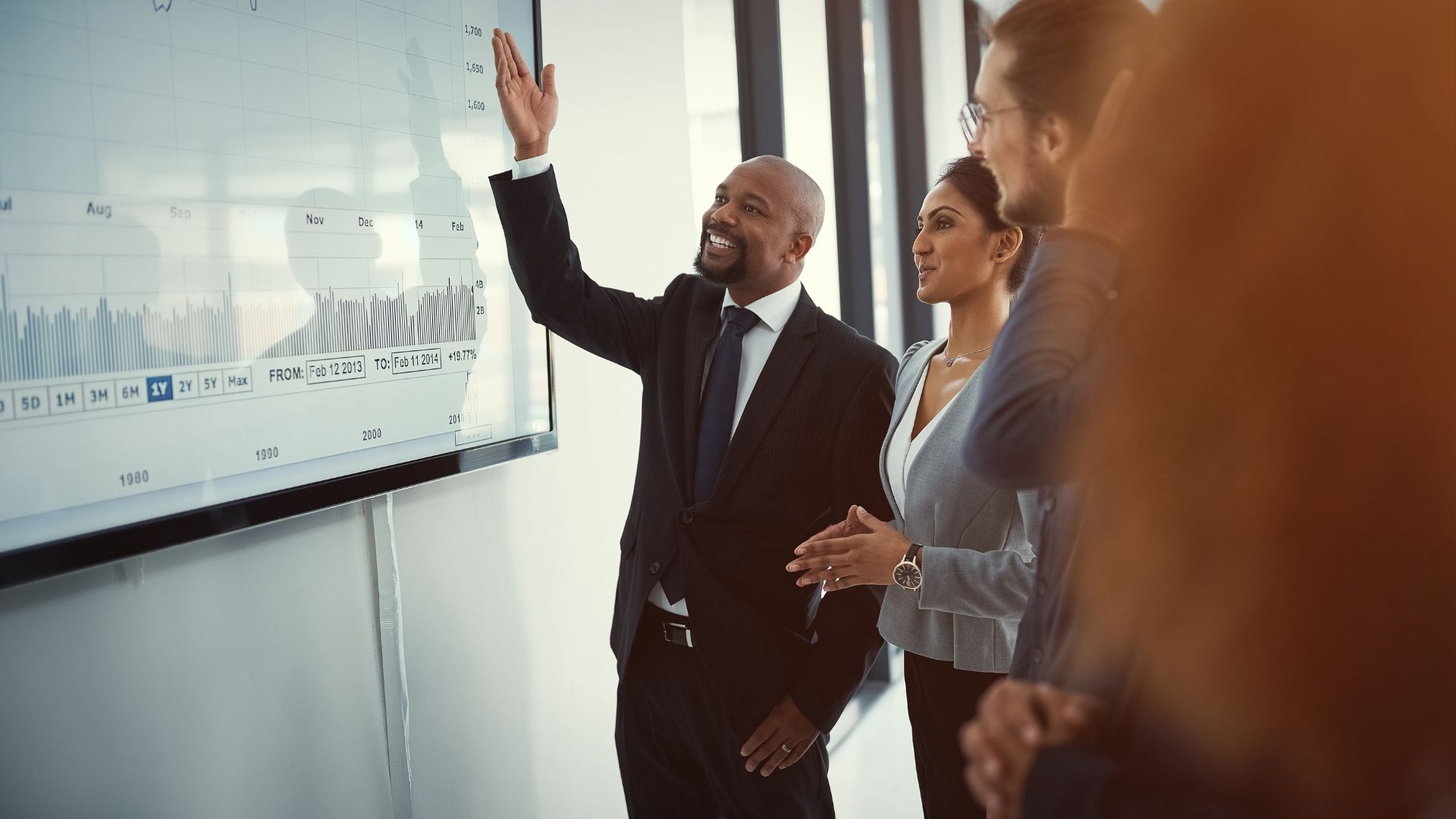 A man is pointing to a presentation, explaining it to his colleagues.