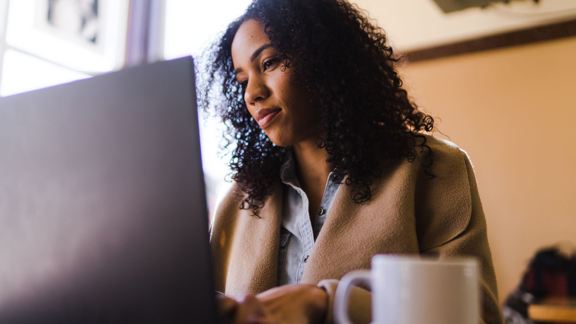 We're looking up at a woman working on her laptop. the bakground around her is slightly blurred.
