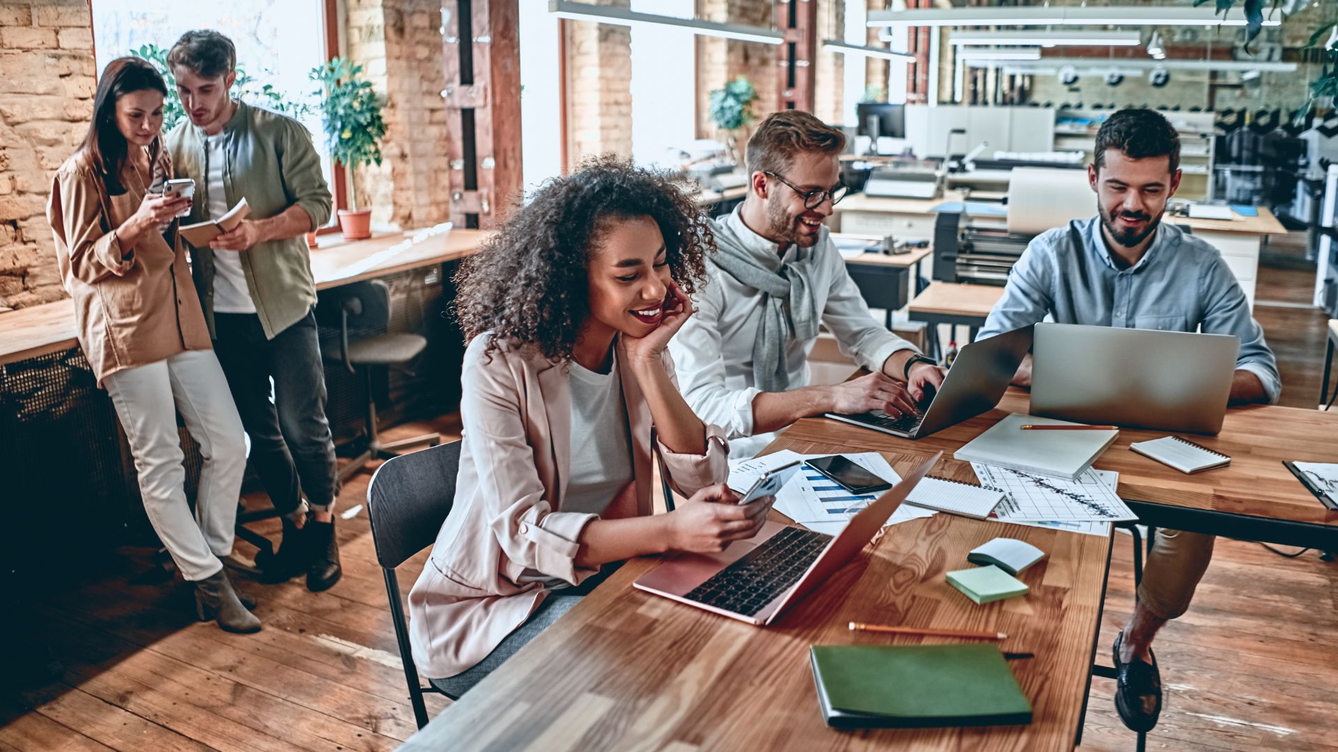 A diverse group of coworkers are working in an office common area.