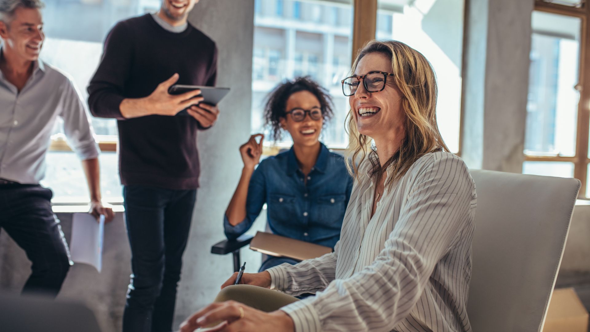 An engaged team is laughing and chatting in a common space.