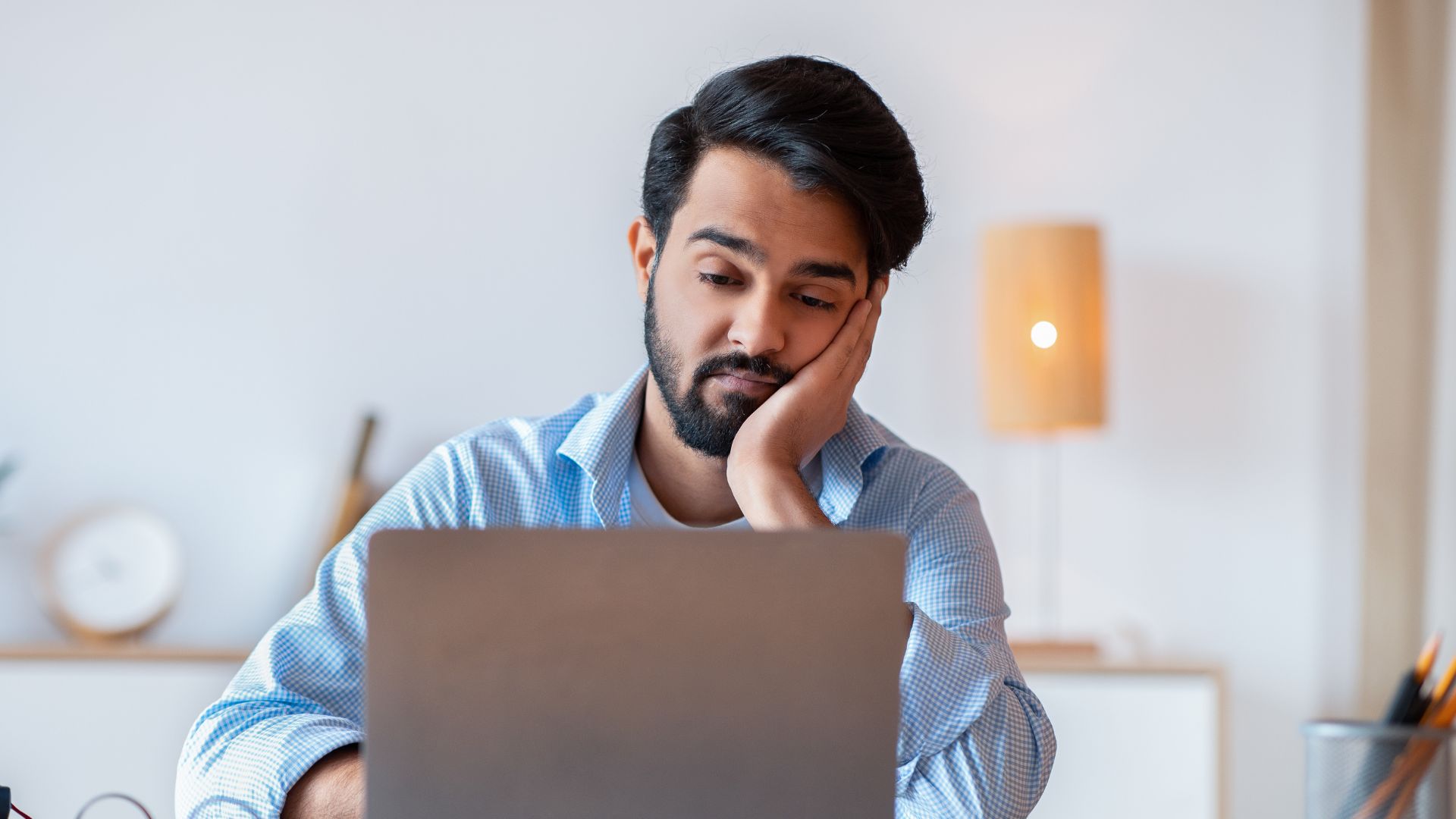 A person is watching a pre-recorded training video with a bored look on their face.