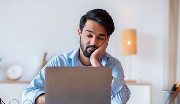 A person is watching a pre-recorded training video with a bored look on their face.