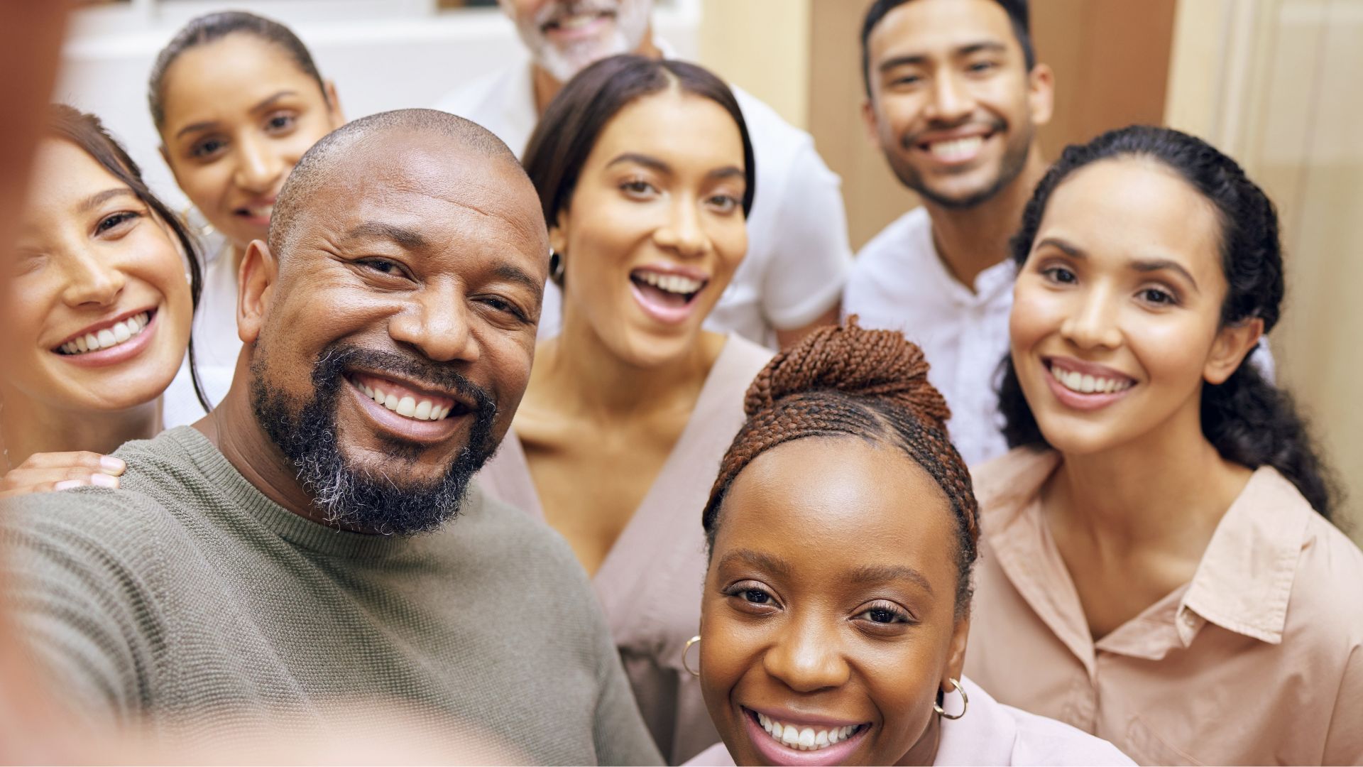 A diverse team of smiling employees taking a group selfie, reflecting a positive and trusting work environment free from micromanagement.