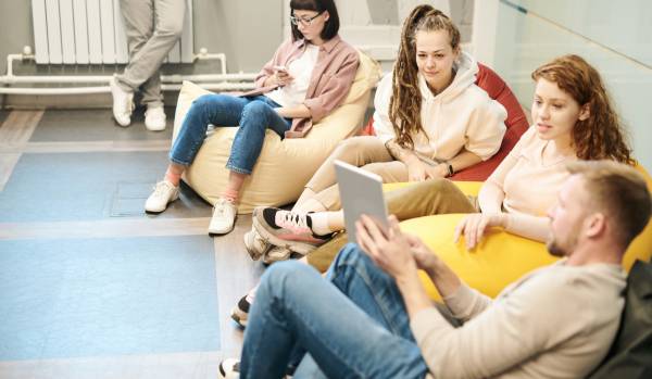 A group of employees sitting on bean bag chairs in an office. They're looking at an iPad.