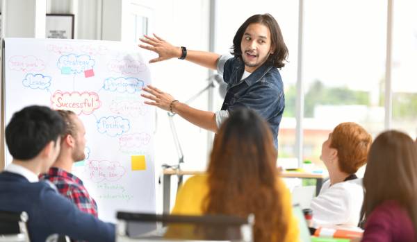 A young man is leading a professional development program for the office.