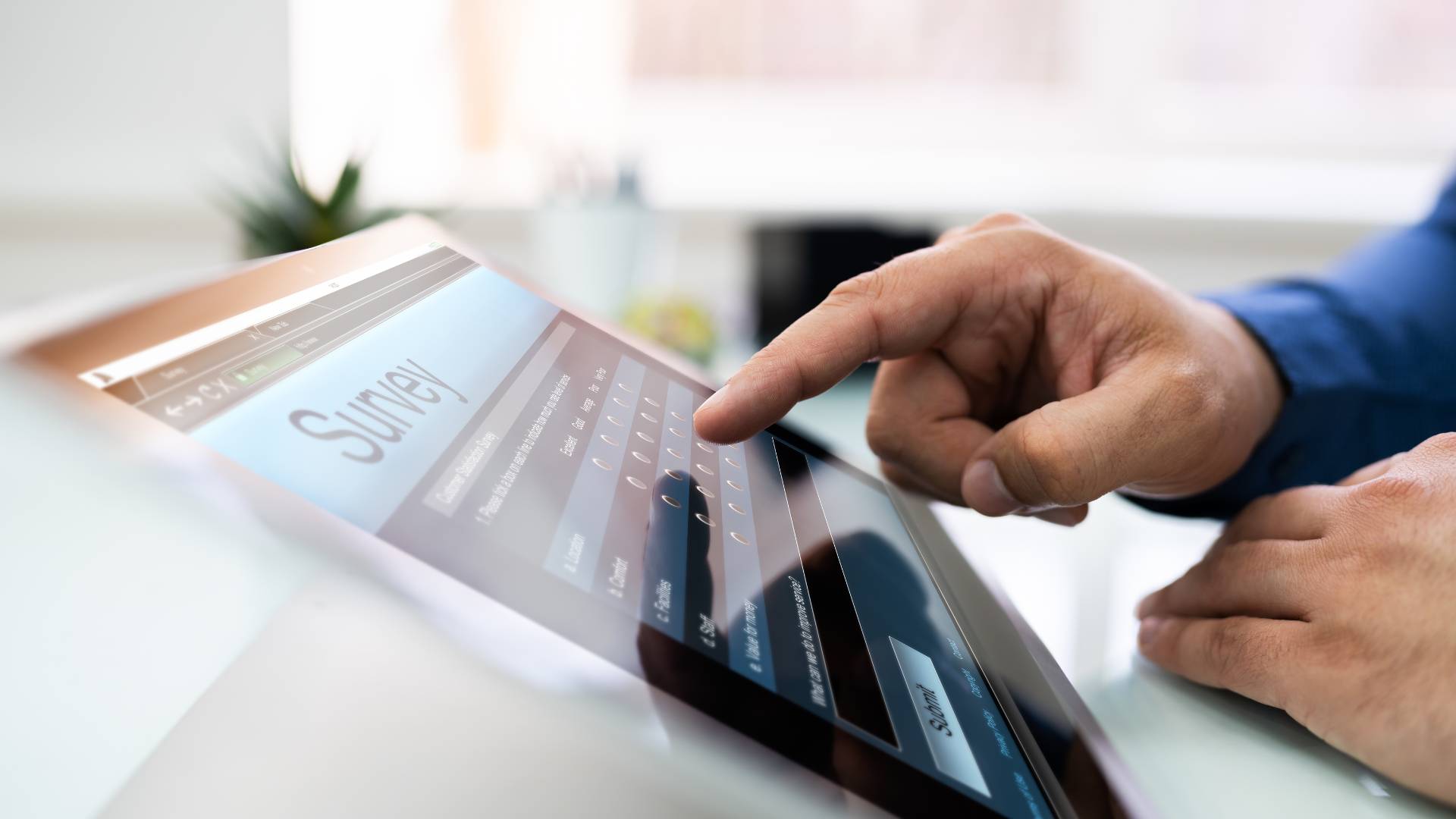 A man's finger is pointing at a screen that reads "Survey".