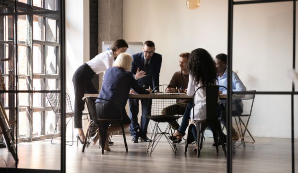 A diverse group of people are engaged in deep conversation around a table in an office space.