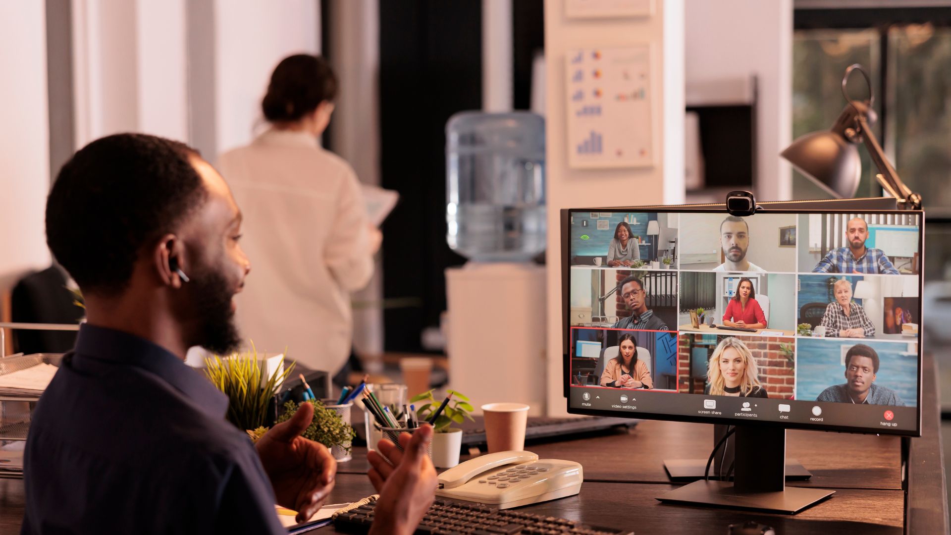 We're looking over the should of a man participating in a virtual training at his monitor with other participants on the screen.