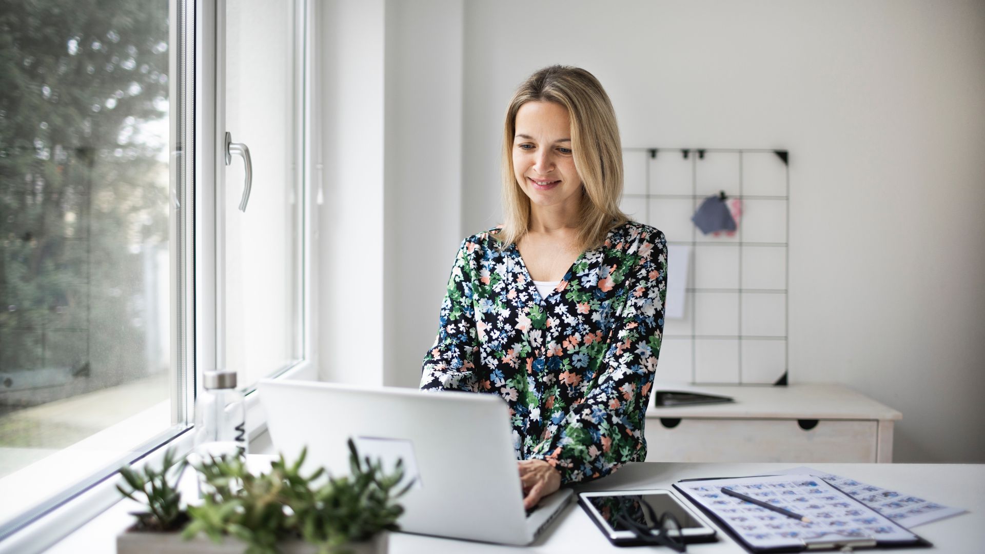 A woman is working on her laptop at a standing desk.