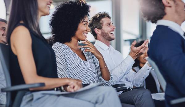 A diverse row of seated training participants in an office are smiling an laughing