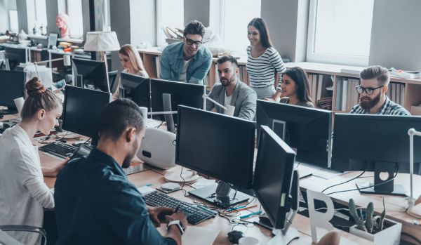 A diverse team of people are working in an open concept office on an AI rollout plan.