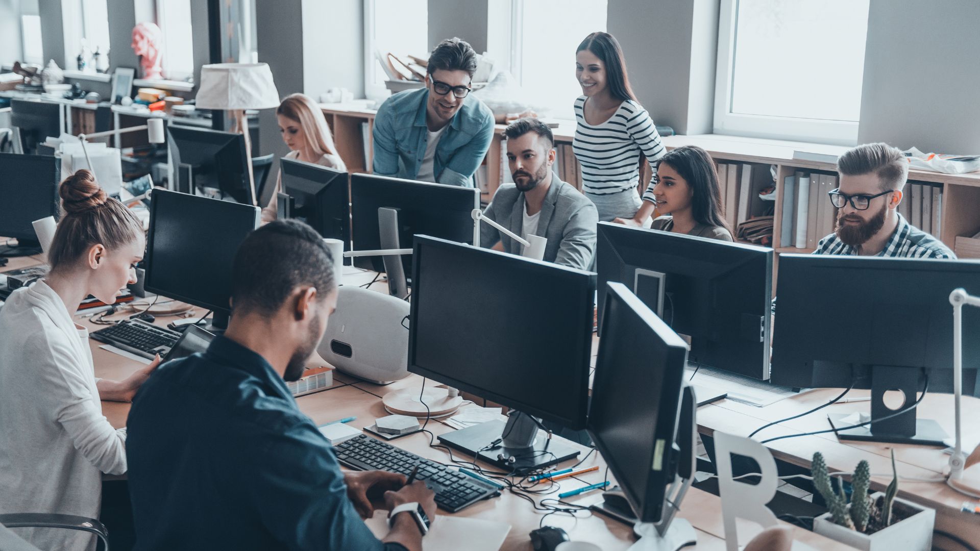 A diverse team of people are working in an open concept office on an AI rollout plan.