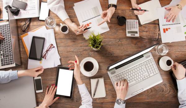 We are looking down at a team working at a conference table with laptops and documents.