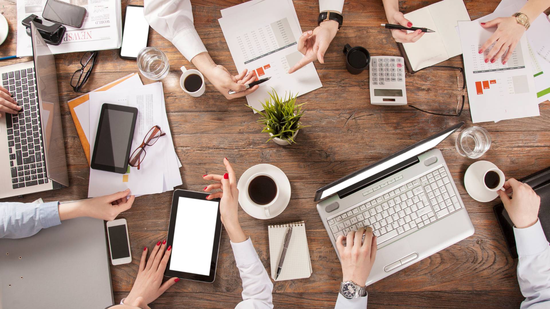 We are looking down at a team working at a conference table with laptops and documents.