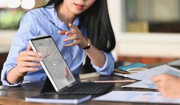A woman is presenting some data on an tablet to a colleague.
