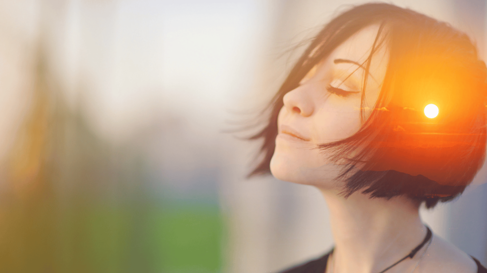 A woman closes her eyes and looks up slightly. She's breathing in deeply and smiling with her mouth closed.
