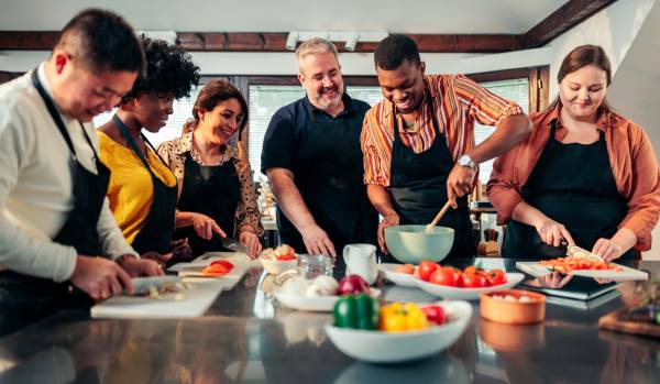A diverse team of people are taking a cooking class together.