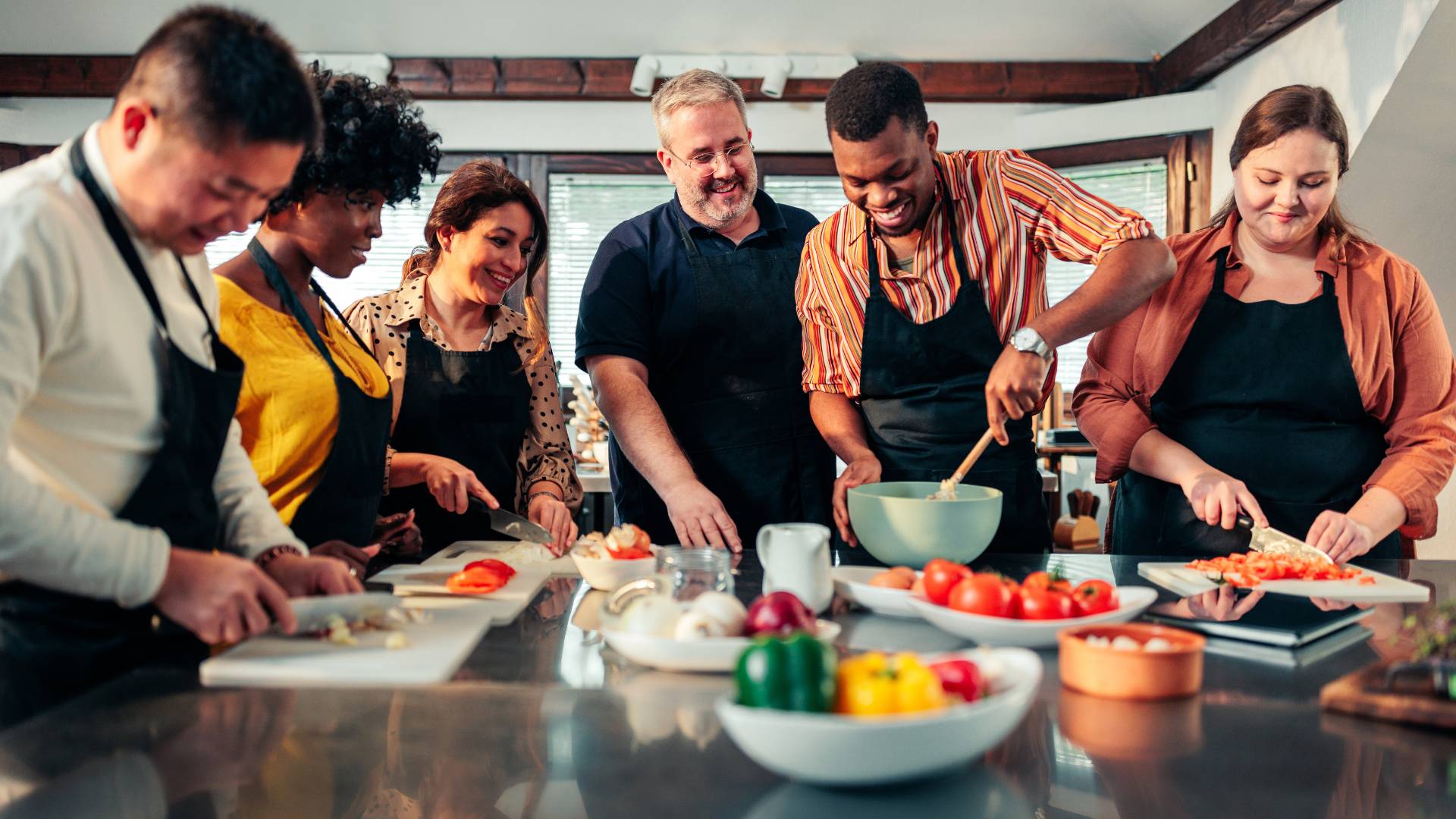 A diverse team of people are taking a cooking class together.