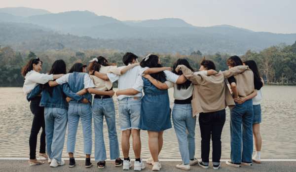 A group of people, with their backs to us, link arms and look at the vista.