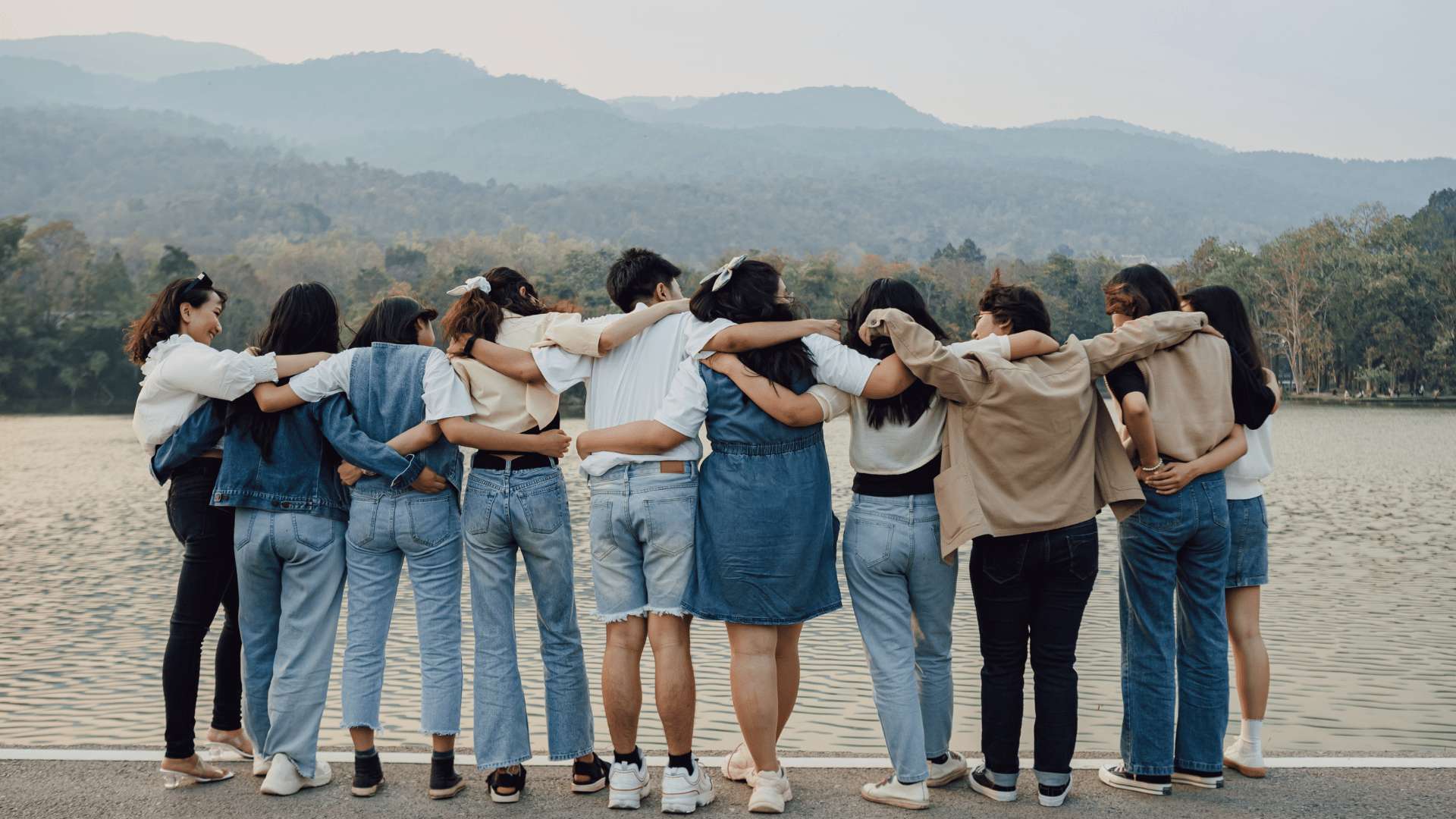 A group of people, with their backs to us, link arms and look at the vista.