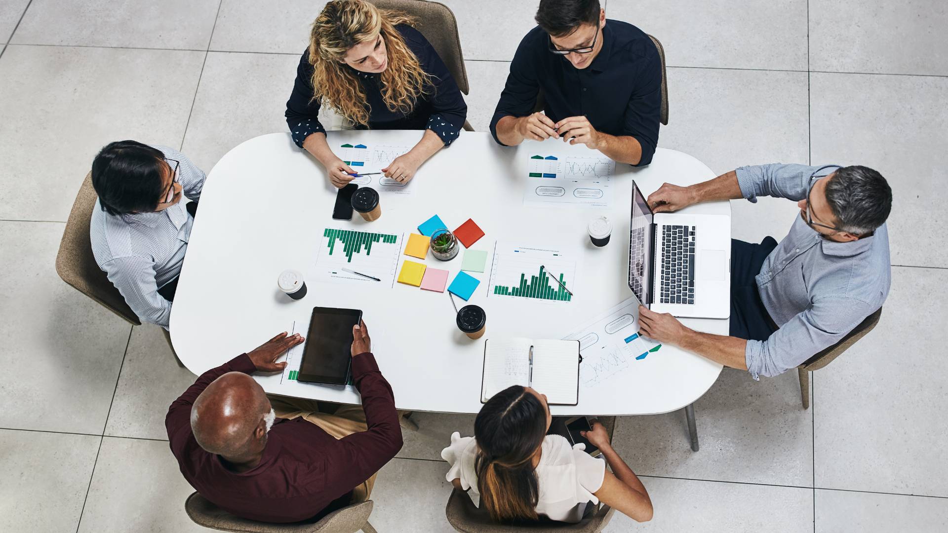 We are looking down from overhead at a team sitting around a conference table, reviewing data trying to make a decision.