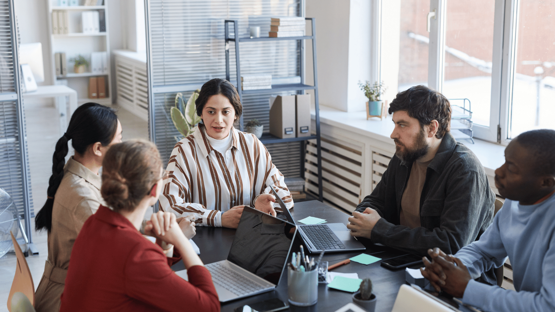 A diverse group of colleagues are sitting around a table discussing a topic.
