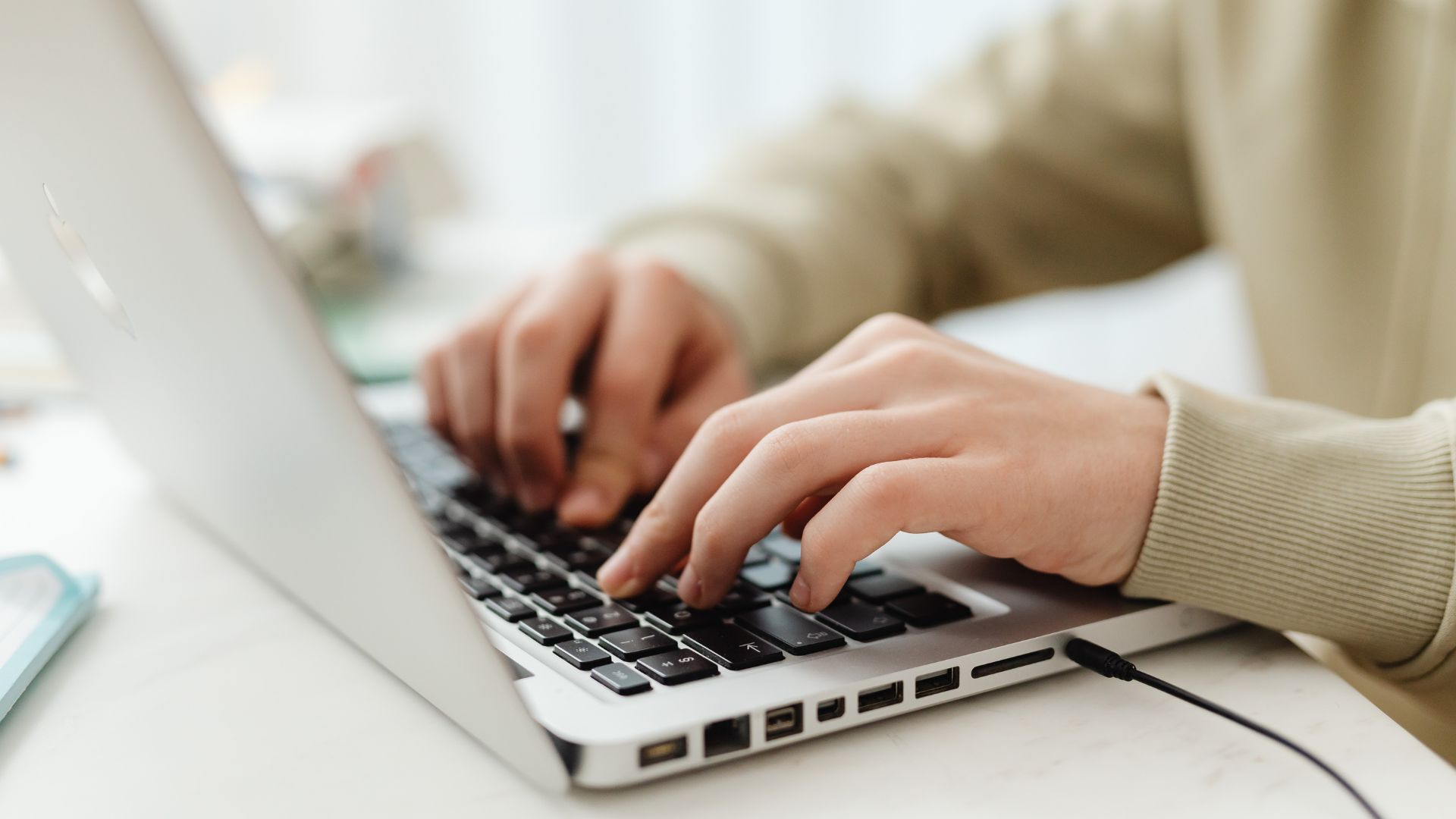 Close-up shot of hands typing on a laptop as the person evaluates different learning platforms.