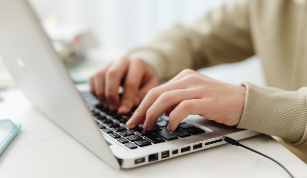 Close-up shot of hands typing on a laptop as the person evaluates different learning platforms.