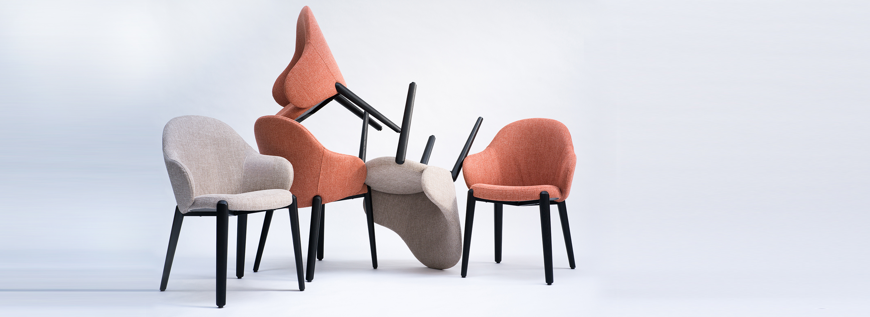 Ein Stuhl Cleo mit Armlehnen von formstelle für May mit Füßen aus Holz und Stoffpolster an einem Tisch von der Seite in sehr dunkler Atmosphäre.