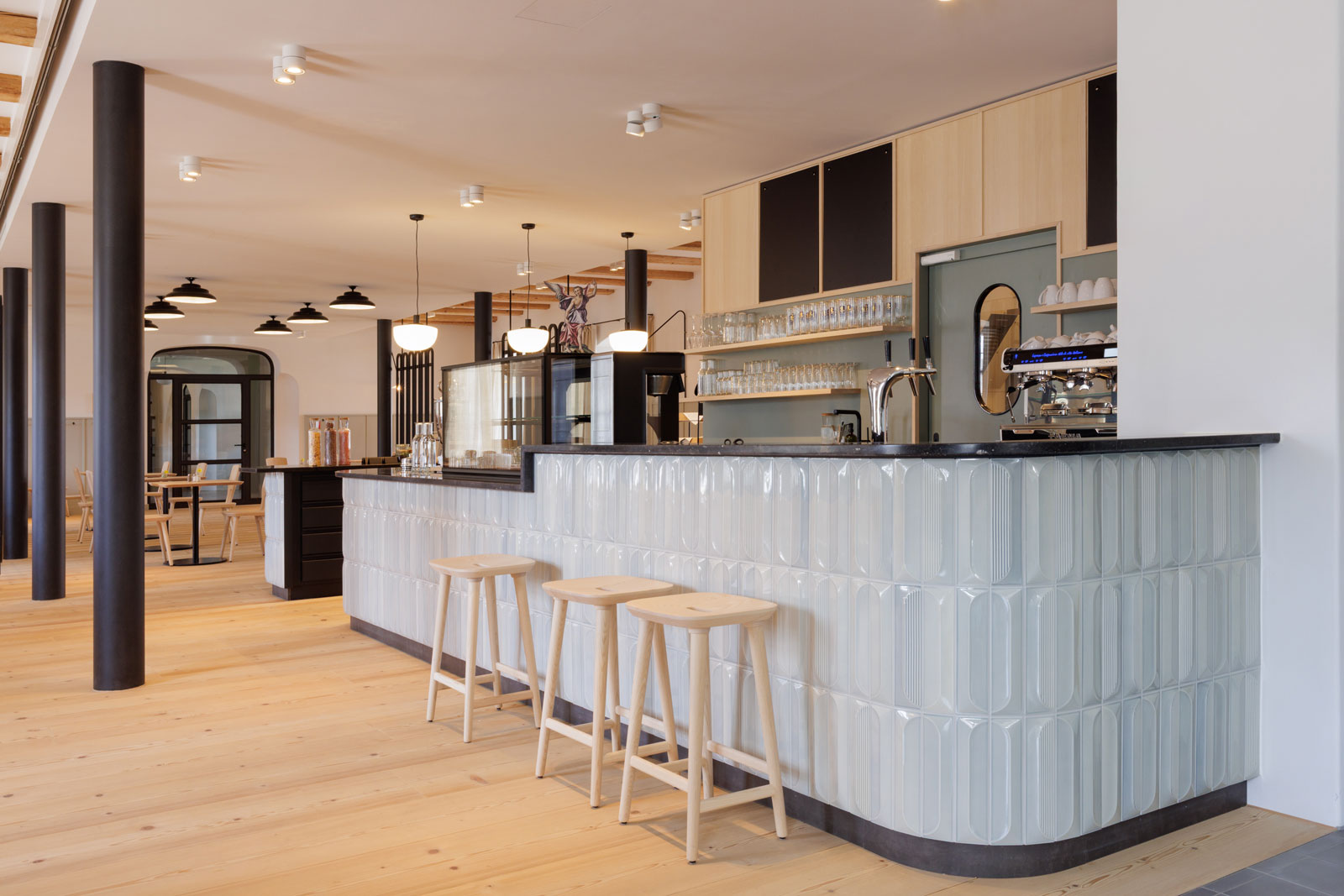 Perspektivansicht des Cafés im Erdgeschoss des Josephstrakts des Klosters Beuerberg mit gefliestem Bartresen, Raumteilern, grün gebeizter Vertäfelung, Bistrotischen und Wandleuchten, von formstelle gestaltet.