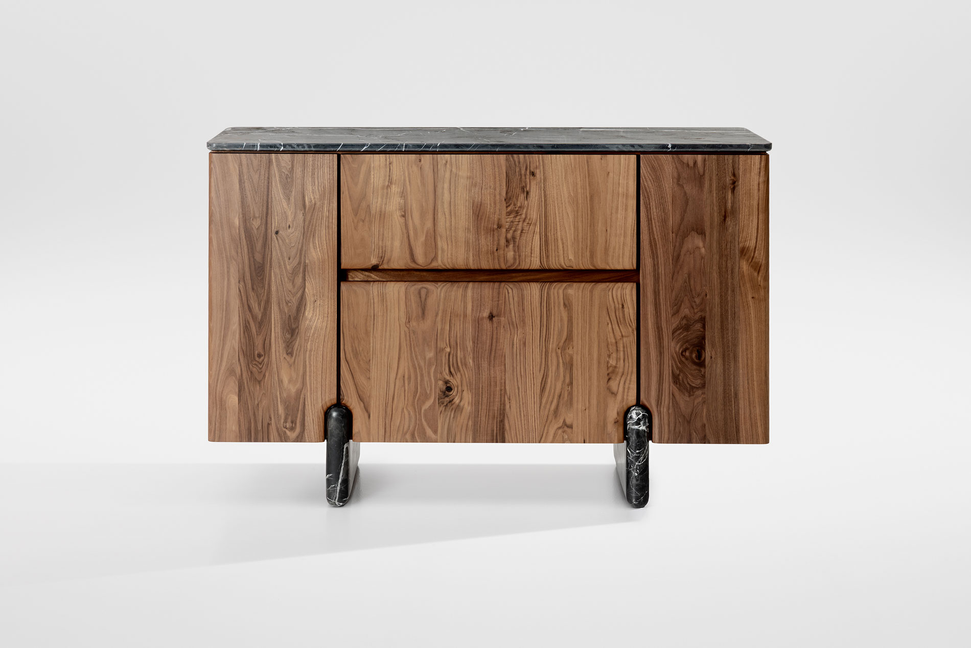 Frontansicht des Sideboards Onde von formstelle für Zeitraum in Nussbaum mit Steinfüßen und Marmor Platte vor hellem Hintergrund.