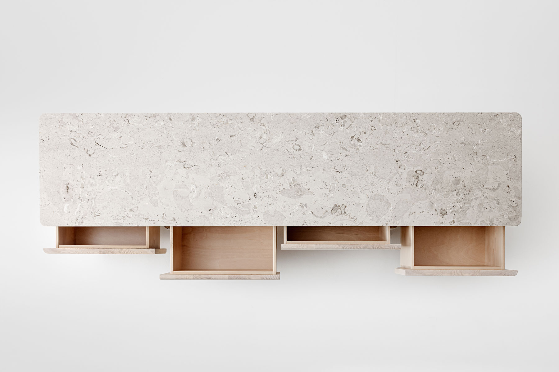 Draufsicht des Sideboards Onde von formstelle für Zeitraum in Esche mit Steinfüßen und Marmor Platte mit ausgezogenen Schubladen vor hellem Hintergrund.