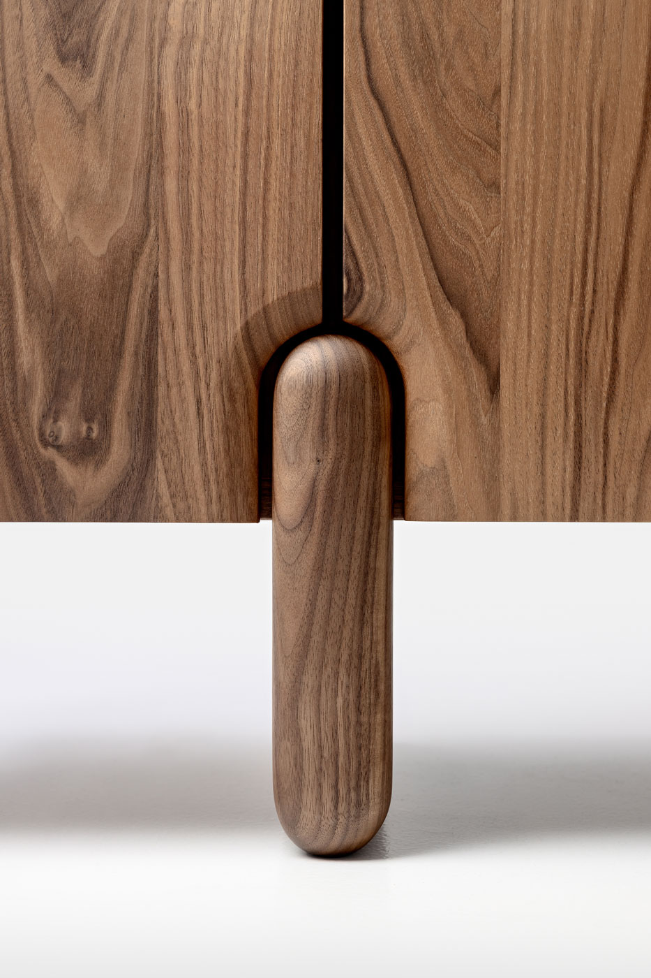 Detailansicht des Fußdetails in Walnuss des Sideboards Onde von formstelle für Zeitraum in Walnuss vor hellem Hintergrund.