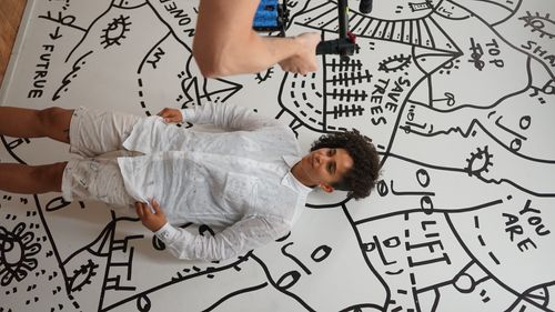 Shantell Martin stands in front of a black-and-white mural while being filmed by a camera operator. Brought to you by Plural, NYC: Experts in Social Media Marketing Strategy and High-Quality Content Production.