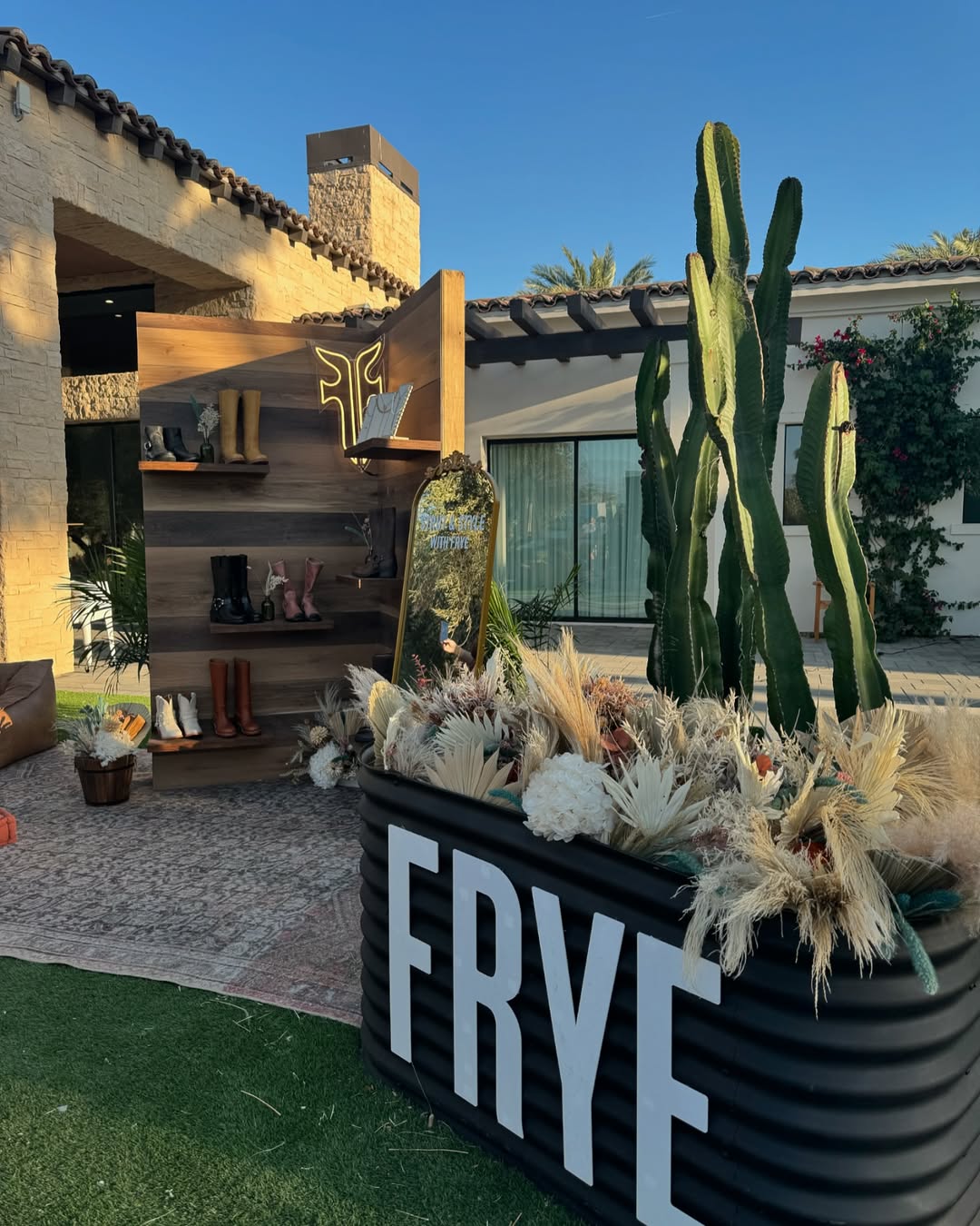 FRYE brand display with boots, cacti, and dried florals at morning desert event. Brought to you by Plural, NYC: Experts in Social Media Marketing Strategy and High-Quality Content Production.