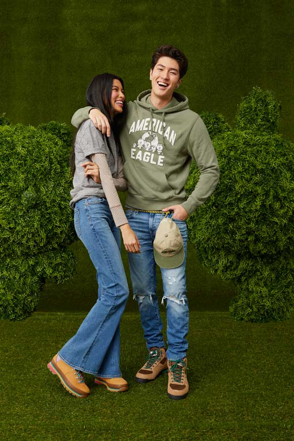  Two American Eagle models in casual wear posing against a green hedge. Brought to you by Plural, NYC: Experts in Social Media Marketing Strategy and High-Quality Content Production.