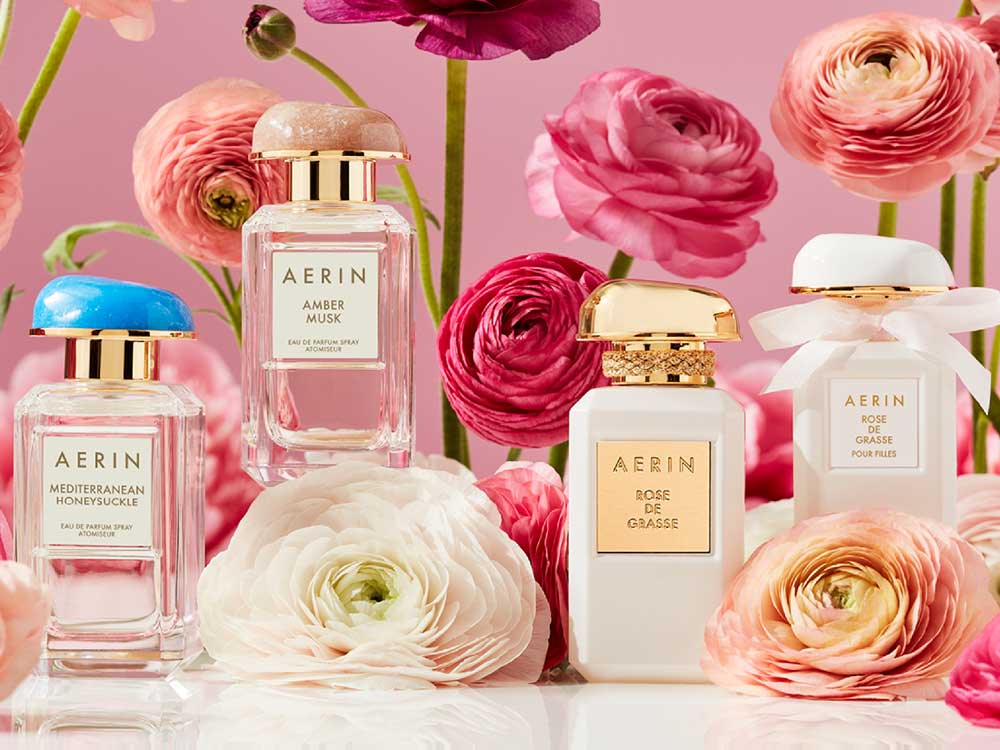 AERIN Rose de Grasse Joyful Bloom perfume bottle with white roses and decorative boxes. Image courtesy of Plural, NYC - Social Media Marketing and Content Production Studio.
