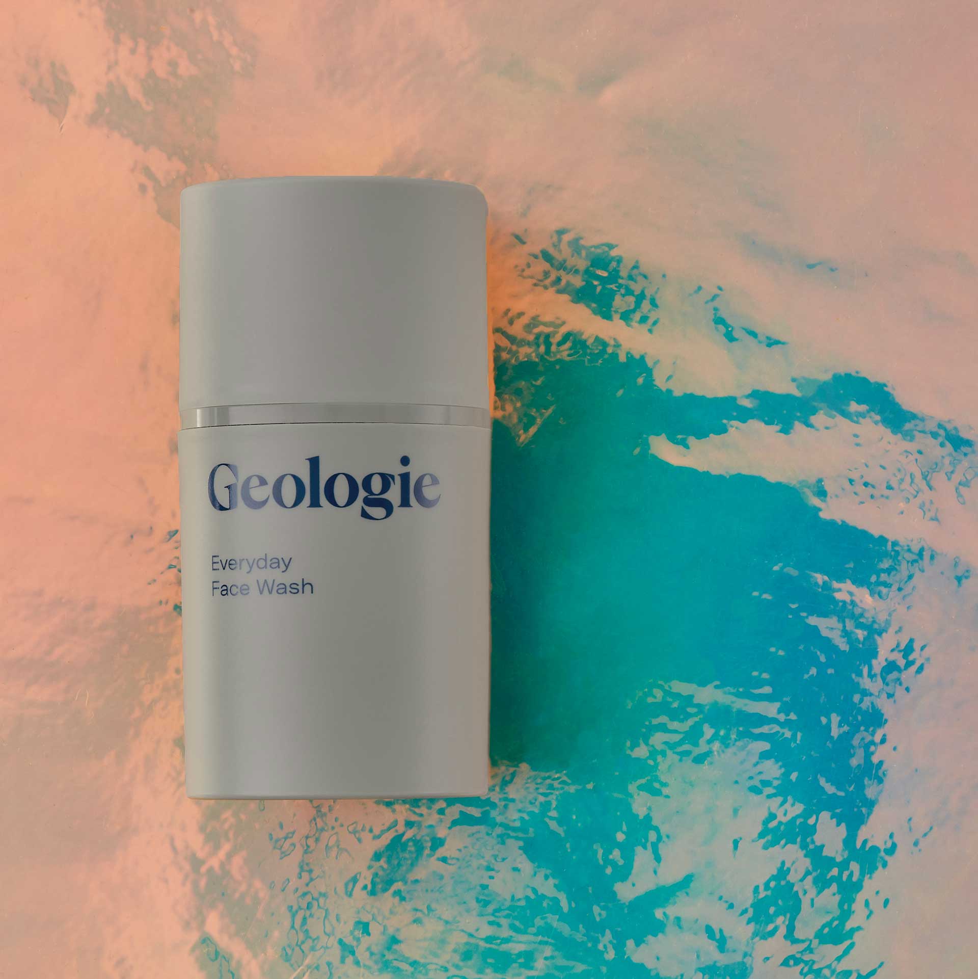 A white cylindrical bottle of Geologie Nourishing Eye Cream placed on a textured background featuring swirls of turquoise blue and peach tonesBrought to you by Plural, NYC: Experts in Social Media Marketing Strategy and High-Quality Content Production.