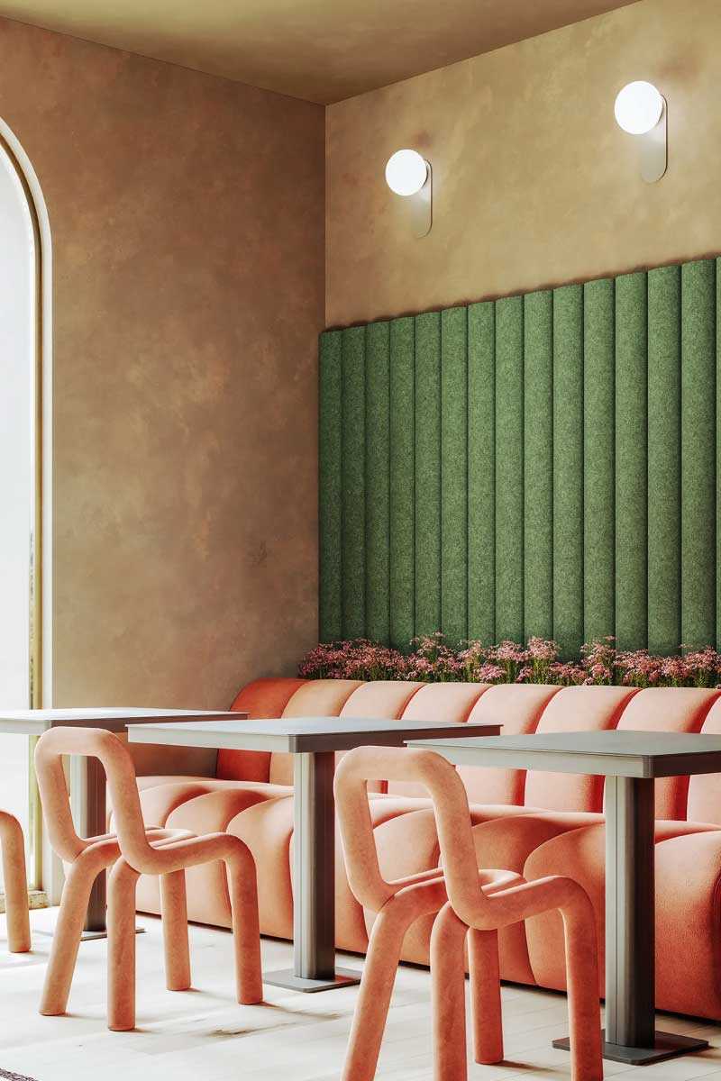 Modern dining area with peach velvet chairs and sofa, green textured Turf wall panel, and pink flowers beneath two round wall lights.