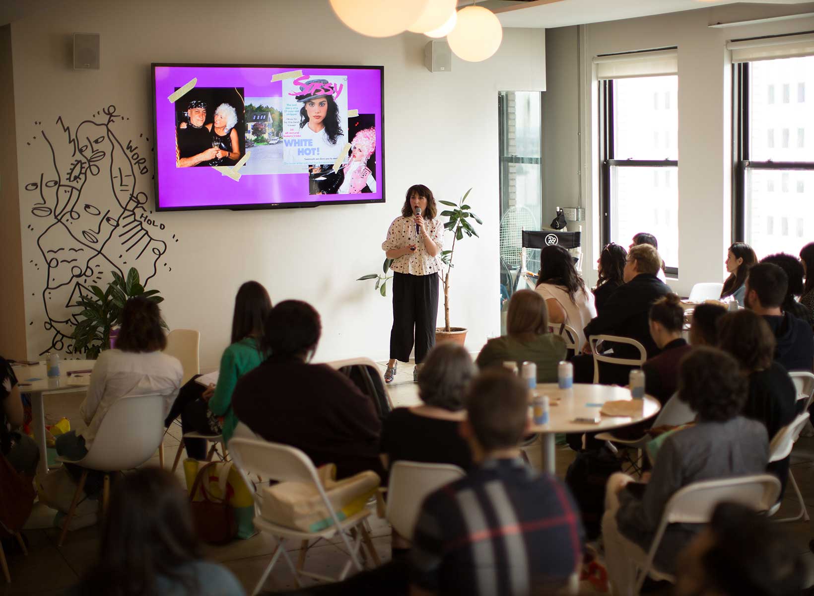 Woman presenting with a slideshow to an audience at the Adobe 99U Conference. Image courtesy of Plural, NYC - Social Media Marketing and Content Production Studio.