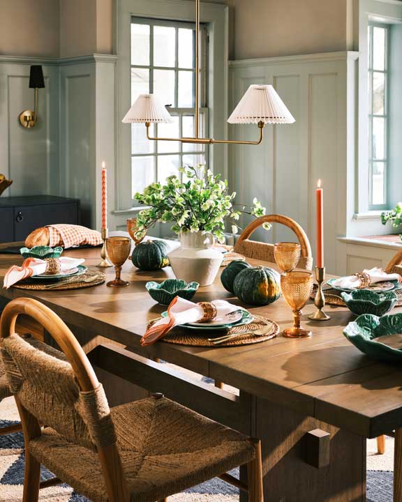 Wooden dining table set for a meal with pumpkins and candles. Brought to you by Plural, NYC: Experts in Social Media Marketing Strategy and High-Quality Content Production.