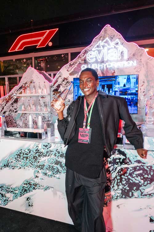 Person smiling and holding a drink in front of an Evian GLB Hydration display with F1 logo above.
