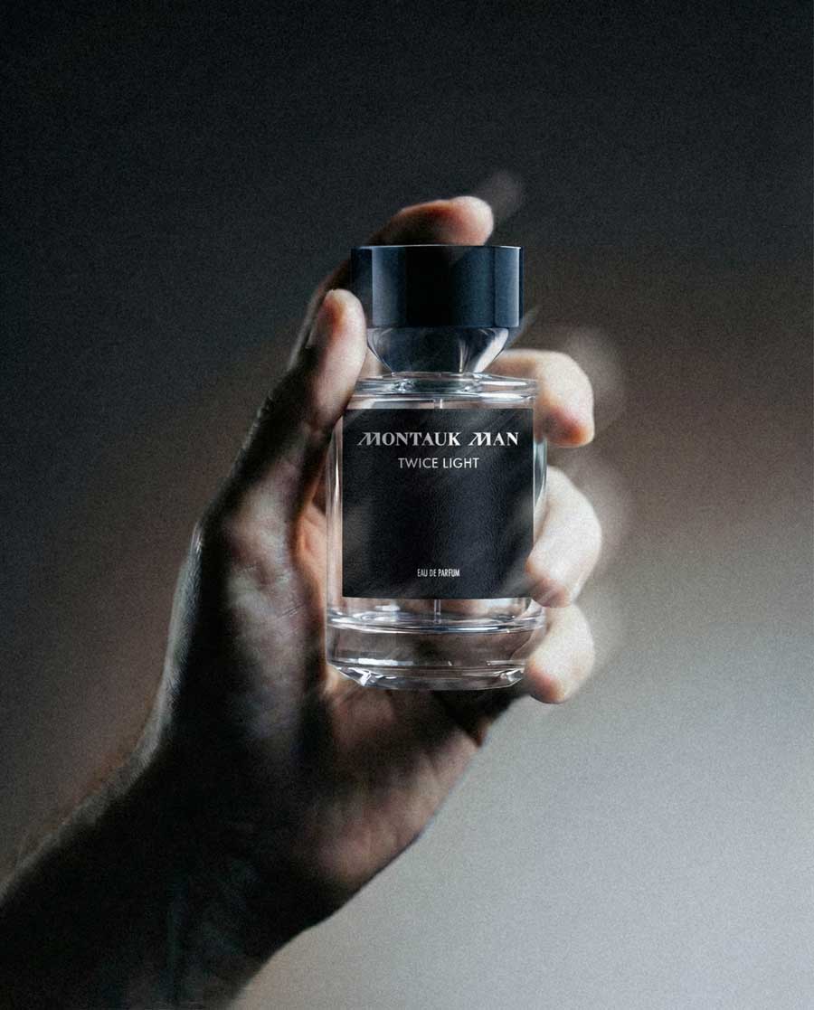 Hand holding a Montauk Man Twice Light eau de parfum bottle with black label and cap.