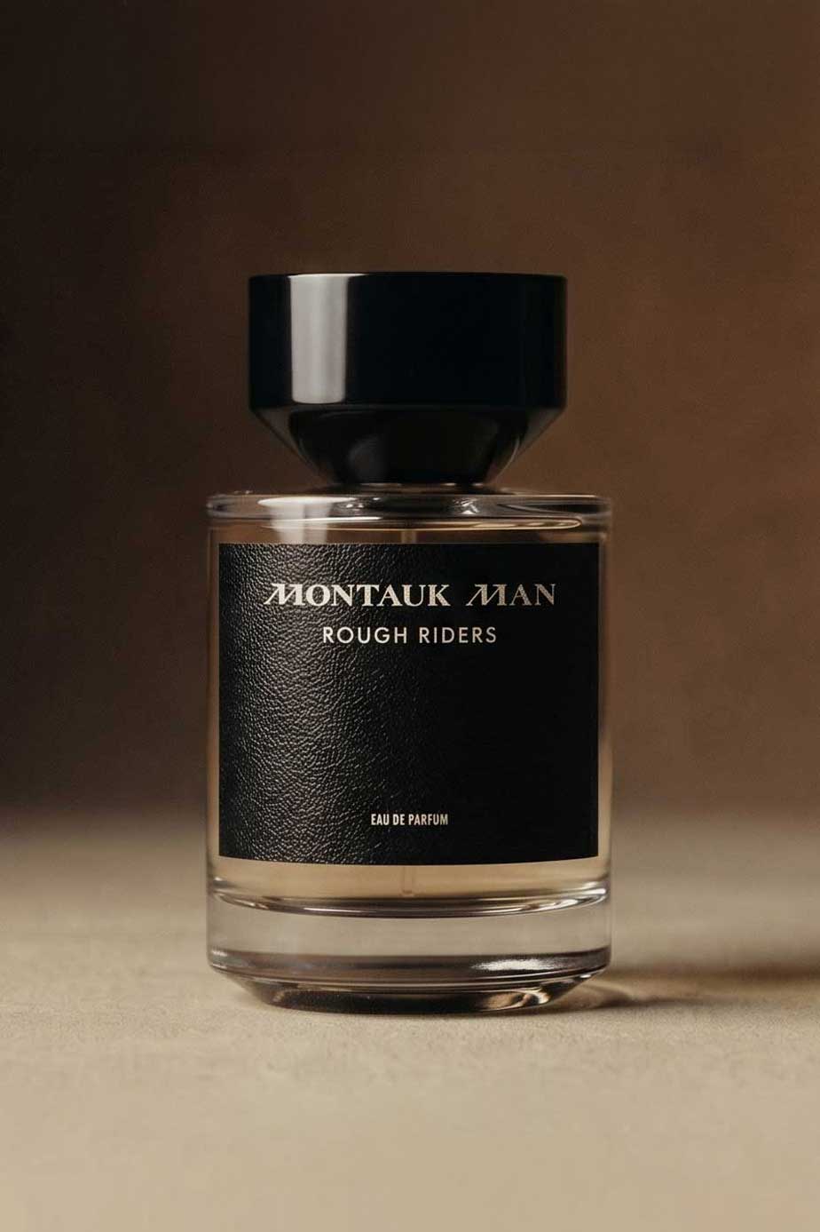 Montauk Man Rough Riders eau de parfum bottle with black label and cap on beige surface.