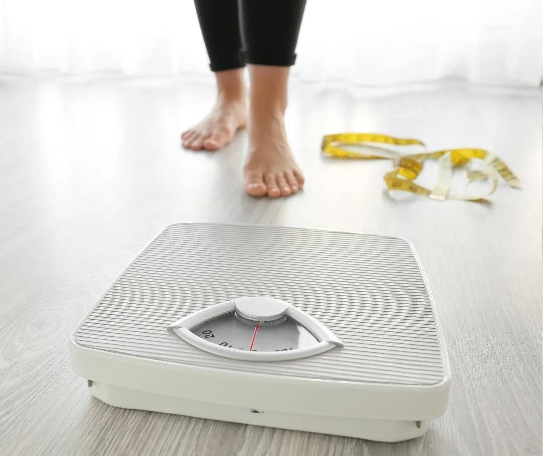 a person about to step on a scale, with measuring tape on the floor