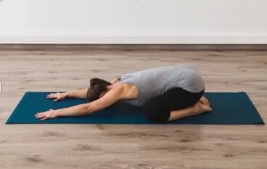 woman in grey and black sportwear doing the child's pose