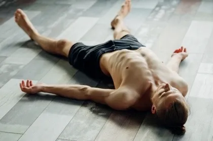 men in shorts laying down doing the corpse pose