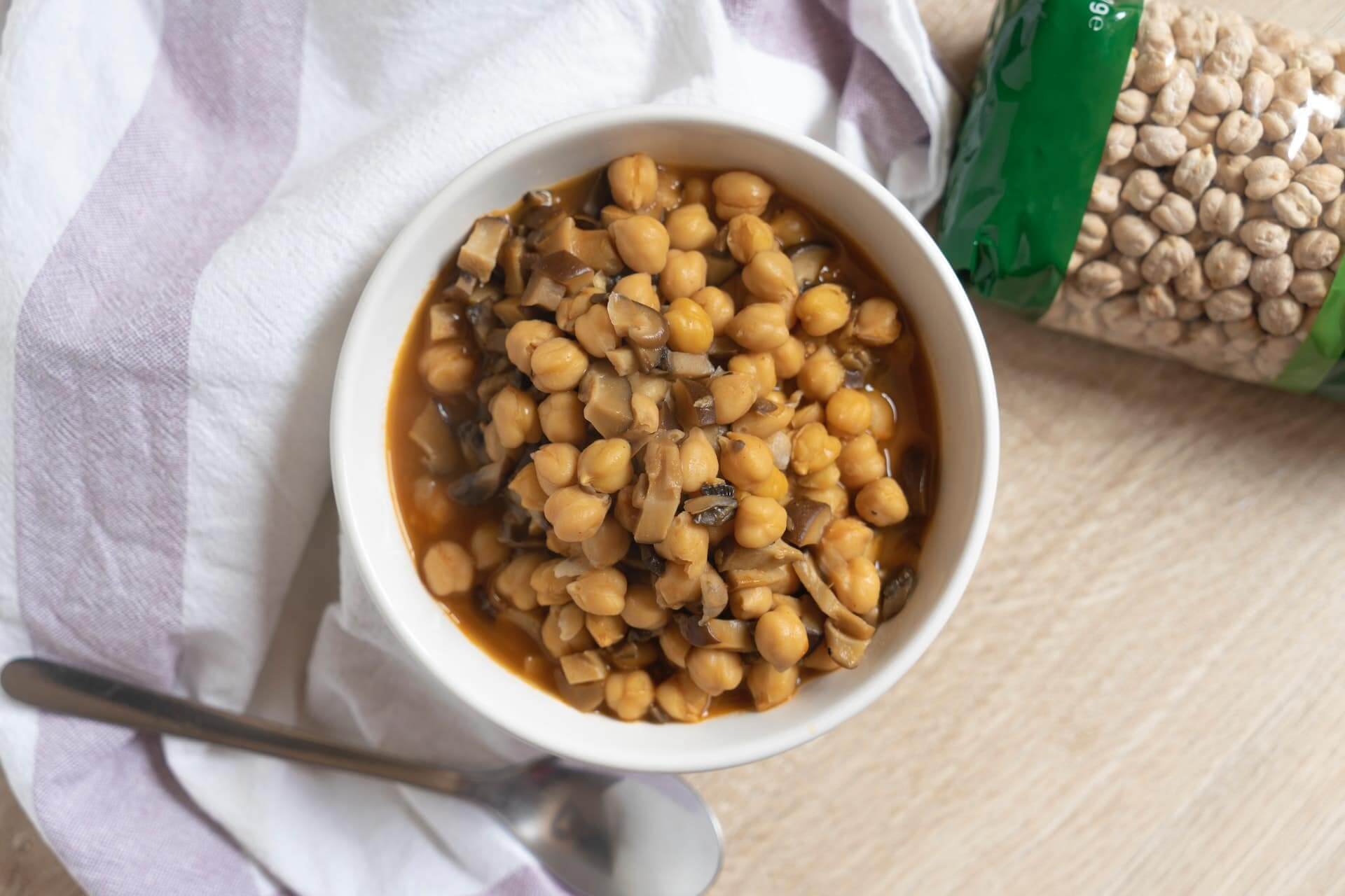 Chickpeas in savory sauce served in white bowl with spoon