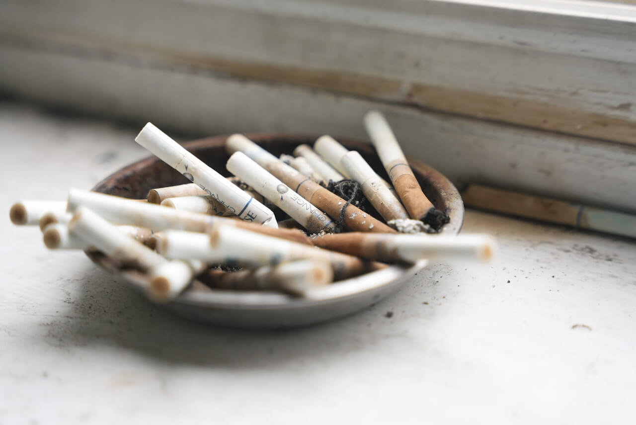 Ashtray filled with used cigarettes on a worn surface