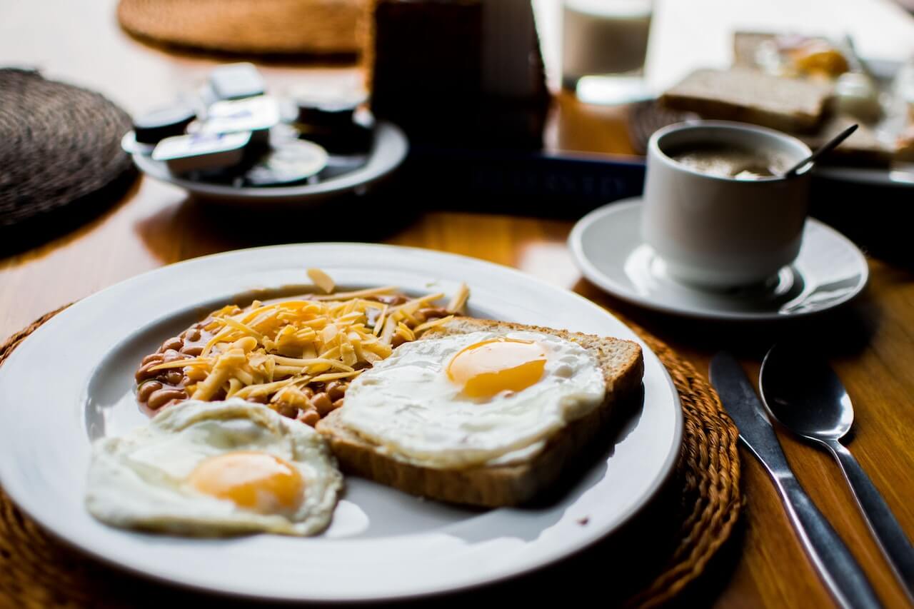 Breakfast plate with sunny-side up eggs, toast, baked beans, and coffee